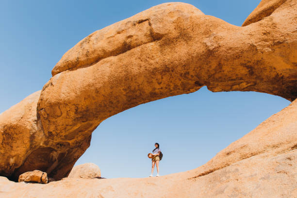 istock Female traveler exploring Spitzkoppe walking inside of the natural arch 1364754746