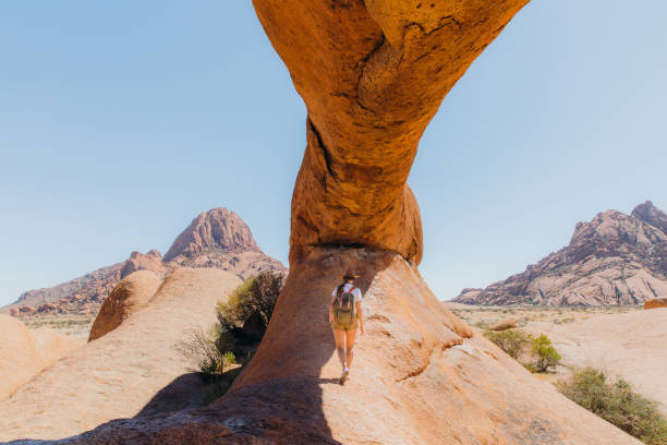 istock Female traveler exploring Spitzkoppe walking inside of the natural arch 1364754757