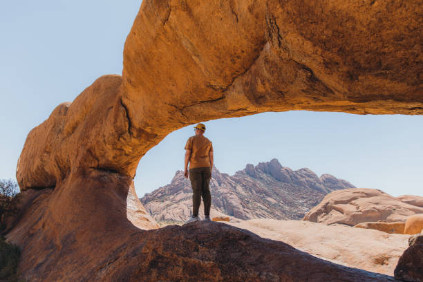 istock Male traveler exploring Spitzkoppe walking inside of the natural arch 1364754759