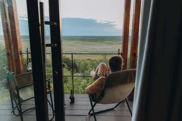 Male traveler contemplating sunset at the wild savannah from the lodge terrace in Etosha National park, Namibia stock photo