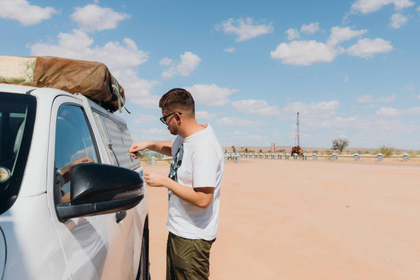 Male traveler having the road trip in Namibia Young man in eyeglasses opening the camper truck preparing for camping in the Namib desert namib sand sea stock pictures, royalty-free photos & images