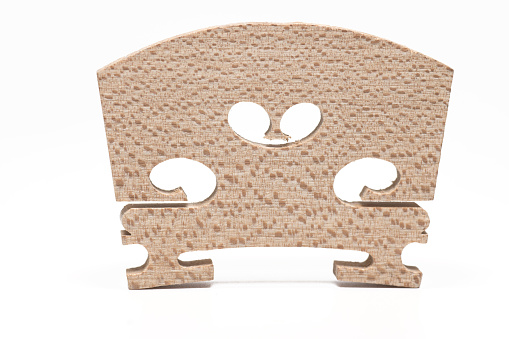 Close up of wooden string bridge for resting strings of violin or viola on white background