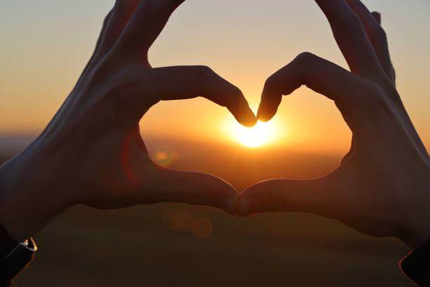 istock Hands in shape of love heart at sunset 1364762455