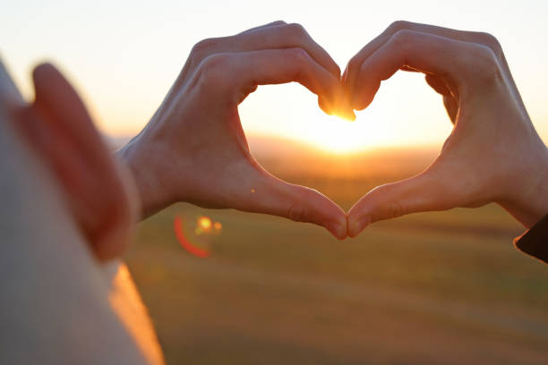 istock Hands in shape of love heart at sunset 1364762494