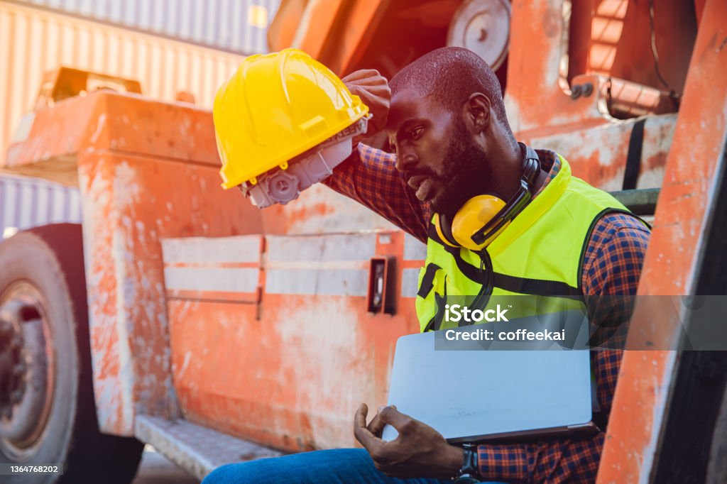 Tired stress worker sweat from hot weather in summer working in port goods cargo shipping logistic ground, Black African race people. Heat - Temperature Stock Photo