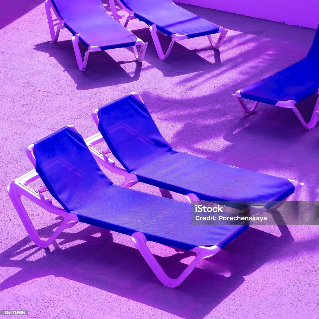 Sun loungers in luxurious resort background. Travel, summer,vacation, relax concept. Purple colors trend Hotel Stock Photo