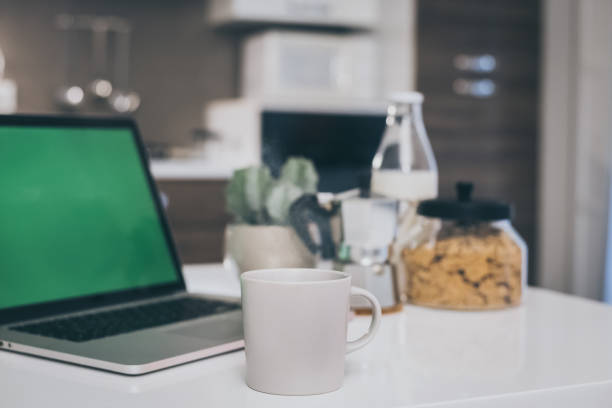 mesa para o café da manhã, cozinha ao fundo. dispositivos naturais de refeição e tecnologia. vista interior de uma casa aconchegante e moderna. millennial, juventude, trabalho em casa, educação domiciliar, conceito de trabalho remoto. - coffee pot audio - fotografias e filmes do acervo