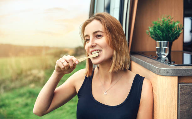 woman brushing her teeth with a bamboo toothbrush outdoors - brushing teeth women toothbrush brushing imagens e fotografias de stock