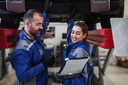 Male and female mechanics working in car repair service.