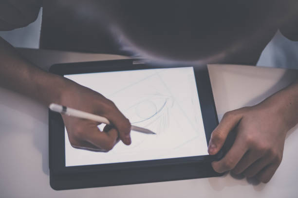 istock Teenager drawing with tablet and virtual pen. Millennial student doing homework with new technology devices. Young boy draw on pad at home. Male hands working with digital pencil on the touch screen. 1364772065
