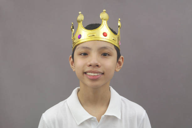 istock Positive Asian boy with gold king crown on head looking at camera and smiling 1364773569