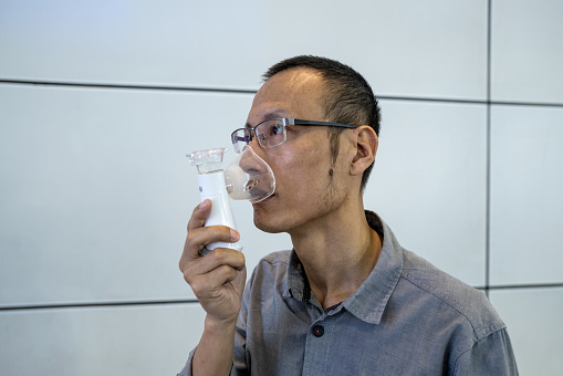 silhouette of asian man using oxygen inhaler