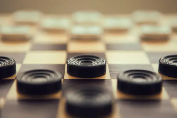 Photo of Checkers white and black on chess-board, very close up