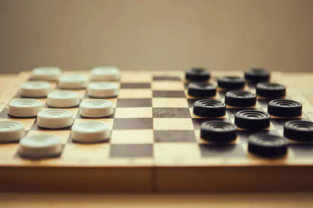 Photo of Checkers white and black on chess-board, close up