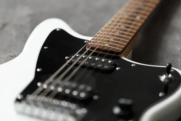 Electric guitar black and white color, detail. Music instruments. Concept international music day. Electrical guitar neck and metal strings. Macrophotography. Soft focus