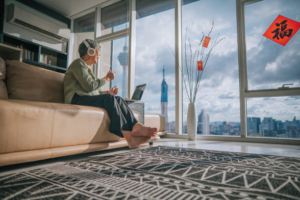 asian chinese senior woman using laptop video conference with her family members during chinese new year in living room of her apartment in city - chinese script text calligraphy grandmother imagens e fotografias de stock