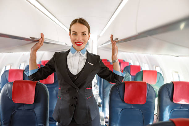 istock Cheerful stewardess standing in airplane passenger salon 1364780351