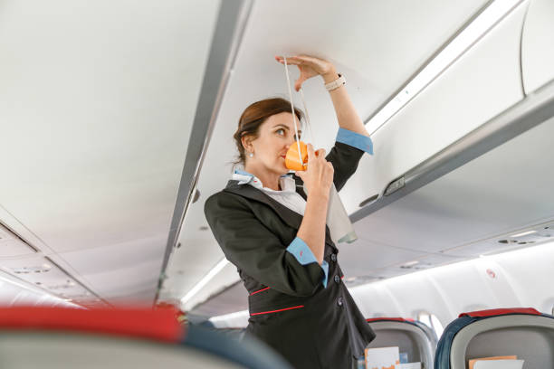 istock Flight attendant demonstrating how to use oxygen mask in airplane 1364780353