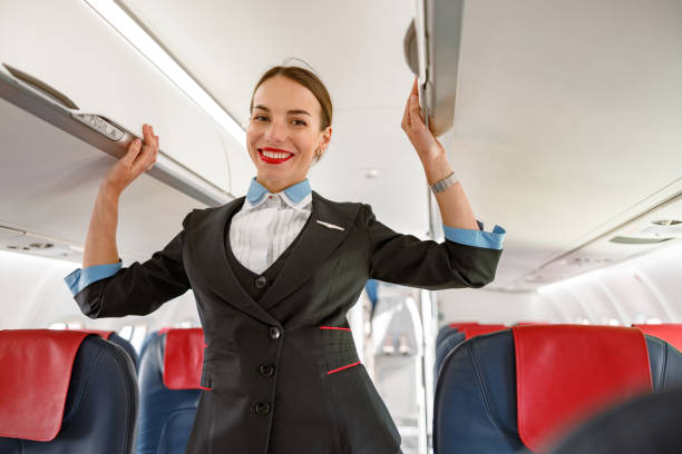 istock Joyful flight attendant standing in airplane passenger salon 1364780356