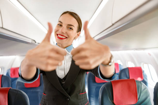istock Joyful woman flight attendant doing thumbs up gesture in airplane 1364780361