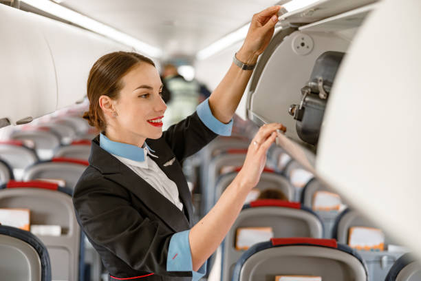 istock Joyful stewardess checking overhead luggage bin in airplane 1364780368