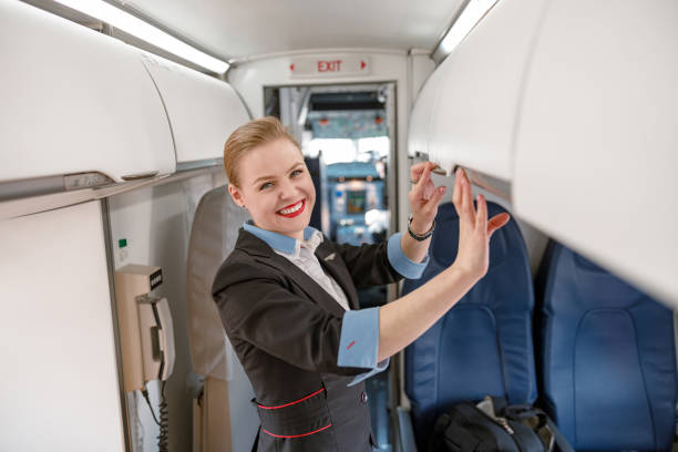 istock Cheerful flight attendant checking overhead shelf in airplane 1364780474