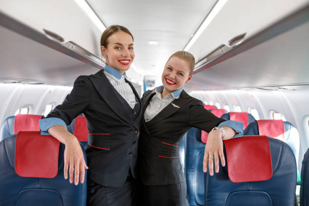 istock Cheerful women stewardesses standing in passenger airplane cabin 1364780521