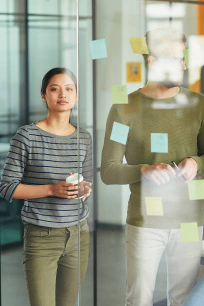 istock Two office colleagues putting reminders on the wall 1364780628
