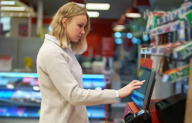Woman pays at self-checkouts in supermarket. stock photo