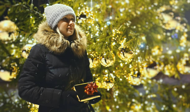 istock Woman with gift waiting near Christmas tree. 1364780701