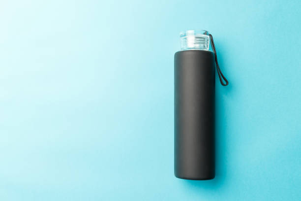 Stylish reusable eco-friendly glass bottle with a black rubberized surface on a blue background. Space for text. Top view. Flat lay. The concept of a lifestyle without plastic and waste Stylish reusable eco-friendly glass bottle with a black rubberized surface on a blue background. Space for text. Top view. Flat lay. The concept of a lifestyle without plastic and waste rubberized stock pictures, royalty-free photos & images