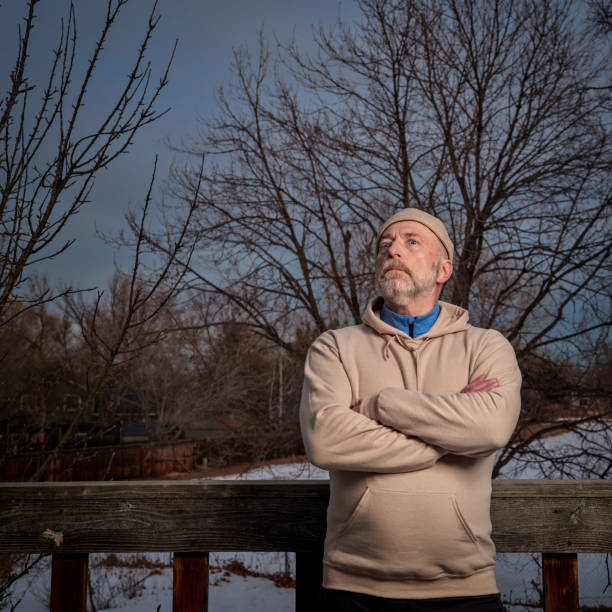 senior man in a sweatshirt is starring at winter sky