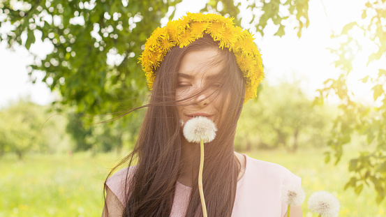 Pretty woman with dandelion in the meadow