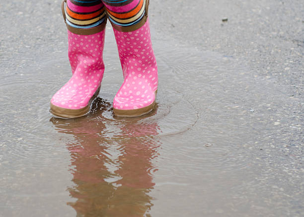 istock little girl splashing in a puddle with rain boots 136479188