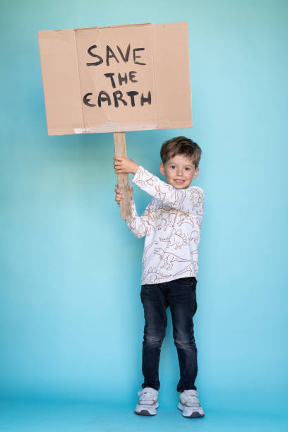 istock Little boy holding a cardboard sign that says SAVE THE EARTH. 1364798719