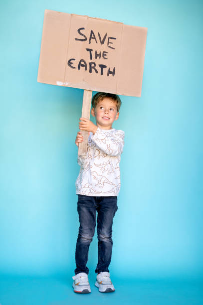 istock Little boy holding a cardboard sign that says SAVE THE EARTH 1364798765