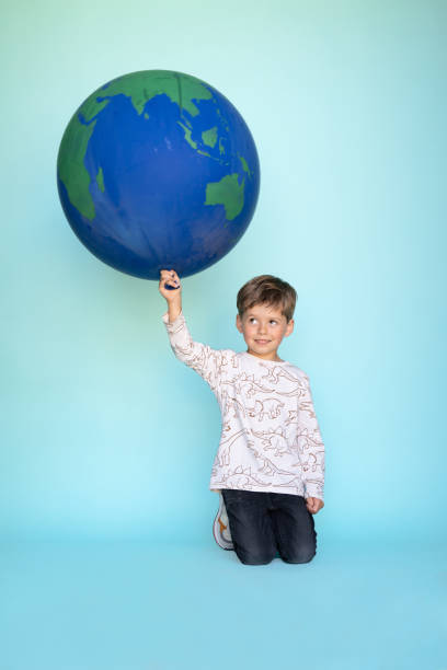 istock Little boy holding balloon globe in his hands 1364798789