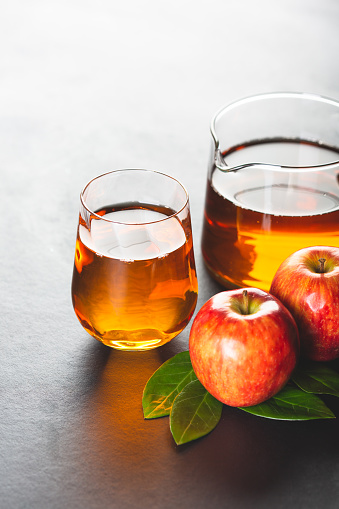Apple Juice in glass and in a jug, with some red apples