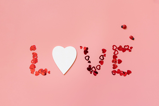 Valentines, love and wedding concept. Lettering love red hearts on pink background. Flat lay, top view.
