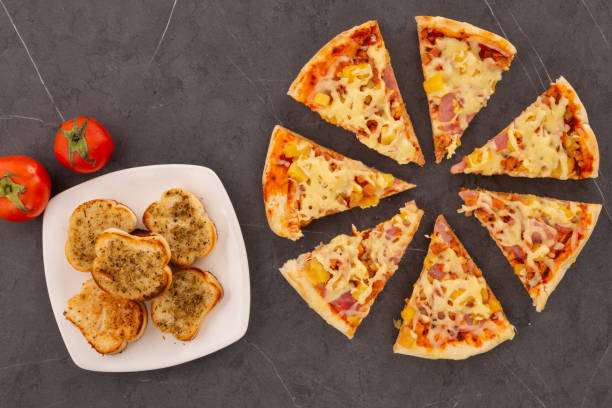 istock table served with crispy garlic bread with oregano, sliced pizza with cheese, pineapple and ham 1364800837