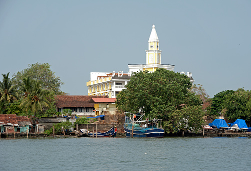 Fort Kochi waterfront with moored barges, Cochin, Kerala, India. Kerala is a colourful Indian state of waterways and tropical rainforest geography on the southwestern Malabar Coast of the country owing its growth to the spice trade created by its Portuguese and British colonial occupiers that is now an attraction for tourists with its river boats and canals