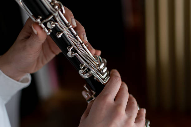 istock Young and beautiful lady, enjoying at her home by playing her clarinet, practicing near the window, enjoing her music and free time. 1364802965