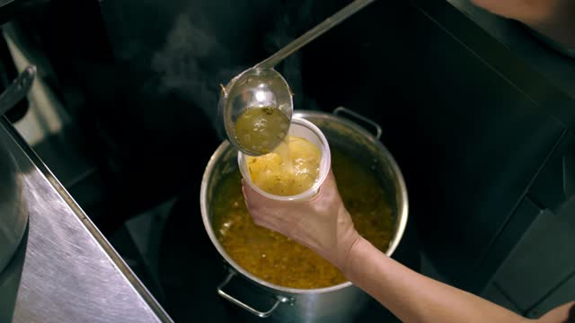 donations. cooking. charity. food delivery. Charities, community soup kitchens are serving free meals to poor and needy. the chef pours hot soup into a food container