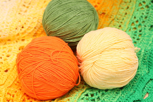 multicolored three balls of wool lie on a knitted tablecloth. High quality photo