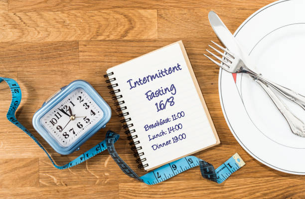 istock Clock, notebook, tape measure and dish with cutlery on a wooden background. 1364813052