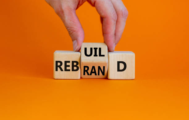 Rebrand and rebuild symbol. Businessman turnsa the wooden cube and changes the word rebrand to rebuild. Beautiful orange table, orange background. Business rebrand and rebuild concept. Copy space. stock photo