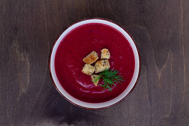red soup. vegetable soup with greens. Bowl of Beetroot cream soup with croutons on a brown wooden background. Healthy dietary lunch. Flat lay, top view. copy space