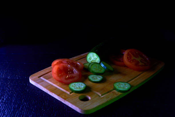 istock Cucumber and tomato, sliced on a dark background 1364821356
