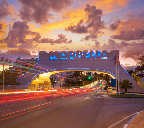 istock Marbella arch welcome sign at sunset with traffic light beams in 1364824244