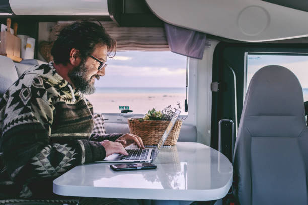 istock Adult man use laptop computer to work inside camper van with roaming phone connection. Concept of modern people lifestyle in smart working or travel digital nomad freedom 1364824346